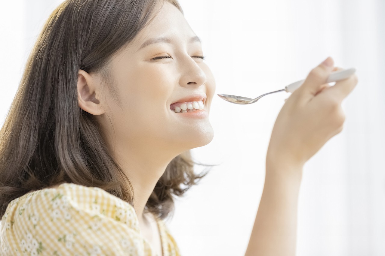 女性がスプーンを持って食事を楽しんでいるメインビジュアル画像