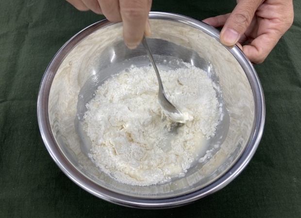 小麦粉をボウルの中に入れる。続いて、水を60ml入れて、スプーンですばやくかき混ぜよう。
