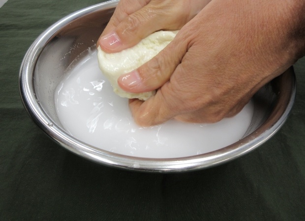 生地を水の入ったボウルに入れて両手で力強くもんでみよう！ひたすらもむ。まだまだもむ！ボウルの中の水が真っ白になったら、水をかえて、またもむ。 （ちなみにこの白いのがでんぷんだよ！）